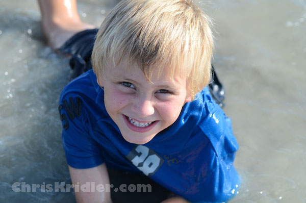 candid photo of boy playing in the waves