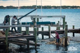 Men struggle with a sunken boat after Hurricane Nicole.