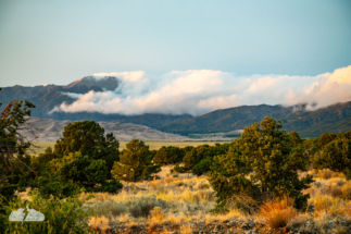 As the sun goes down, the last light touches the soft clouds on the Sangre de Cristo range.