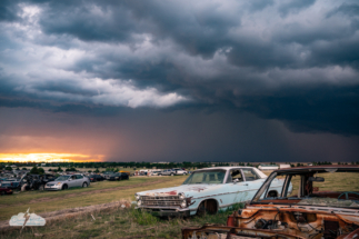The setting sun, the storm, and derelict cars.